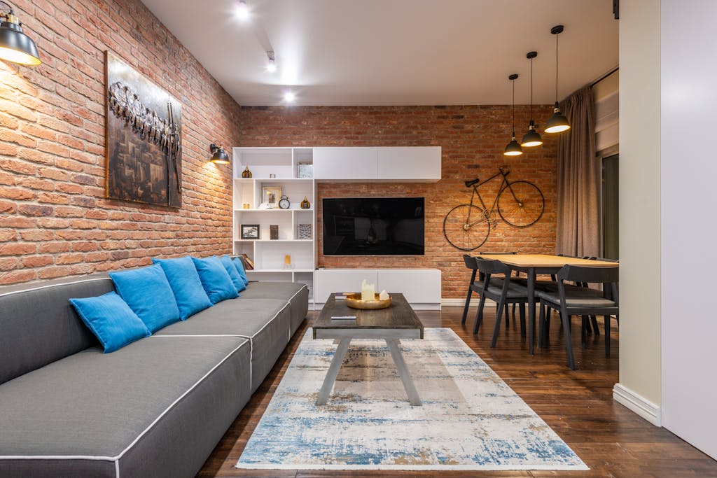 Modern living room with tables and couch under artwork with etching illuminated by lamps in house