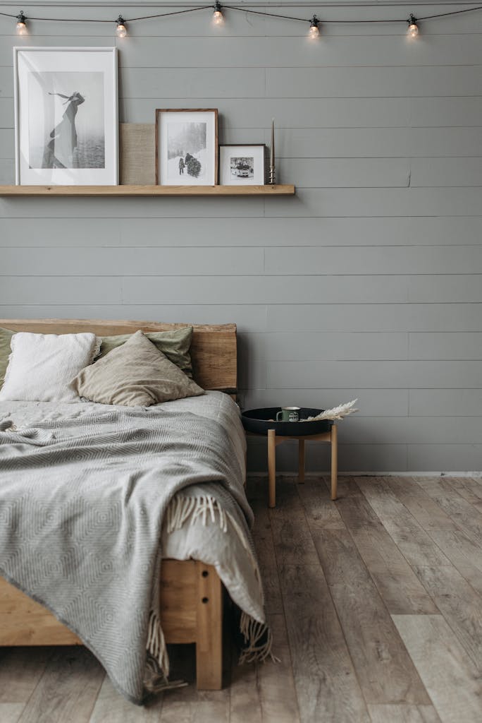 Warm and inviting bedroom featuring a wooden bed, layered blankets, and elegant picture frames on shelf.